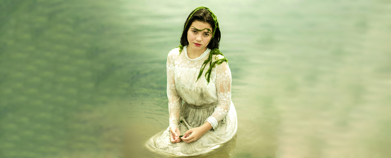 poolplatz.de-blog-poolpflege frau in weißem kleid sitst im wasser, bedeckt mit algen